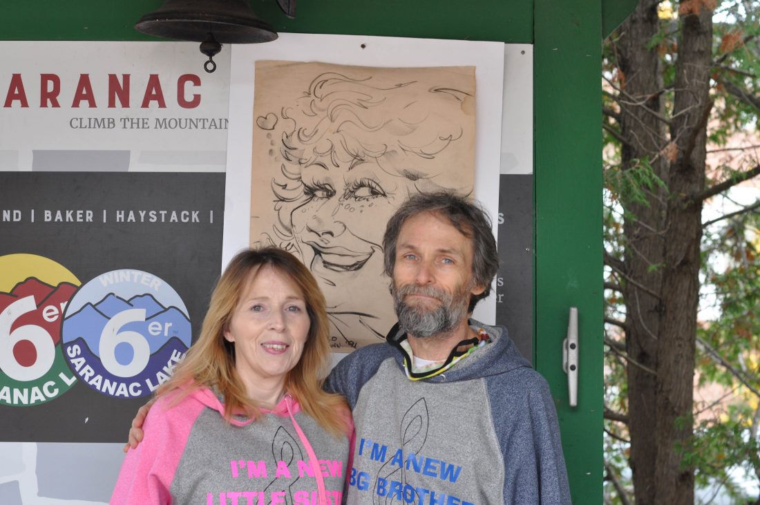 Lauren Peters and her biological brother Richard Auer, who met for the first time last week, stand at Saranac Lake New York’s Berkeley Green Sunday, a drawing of their birthmother behind them.